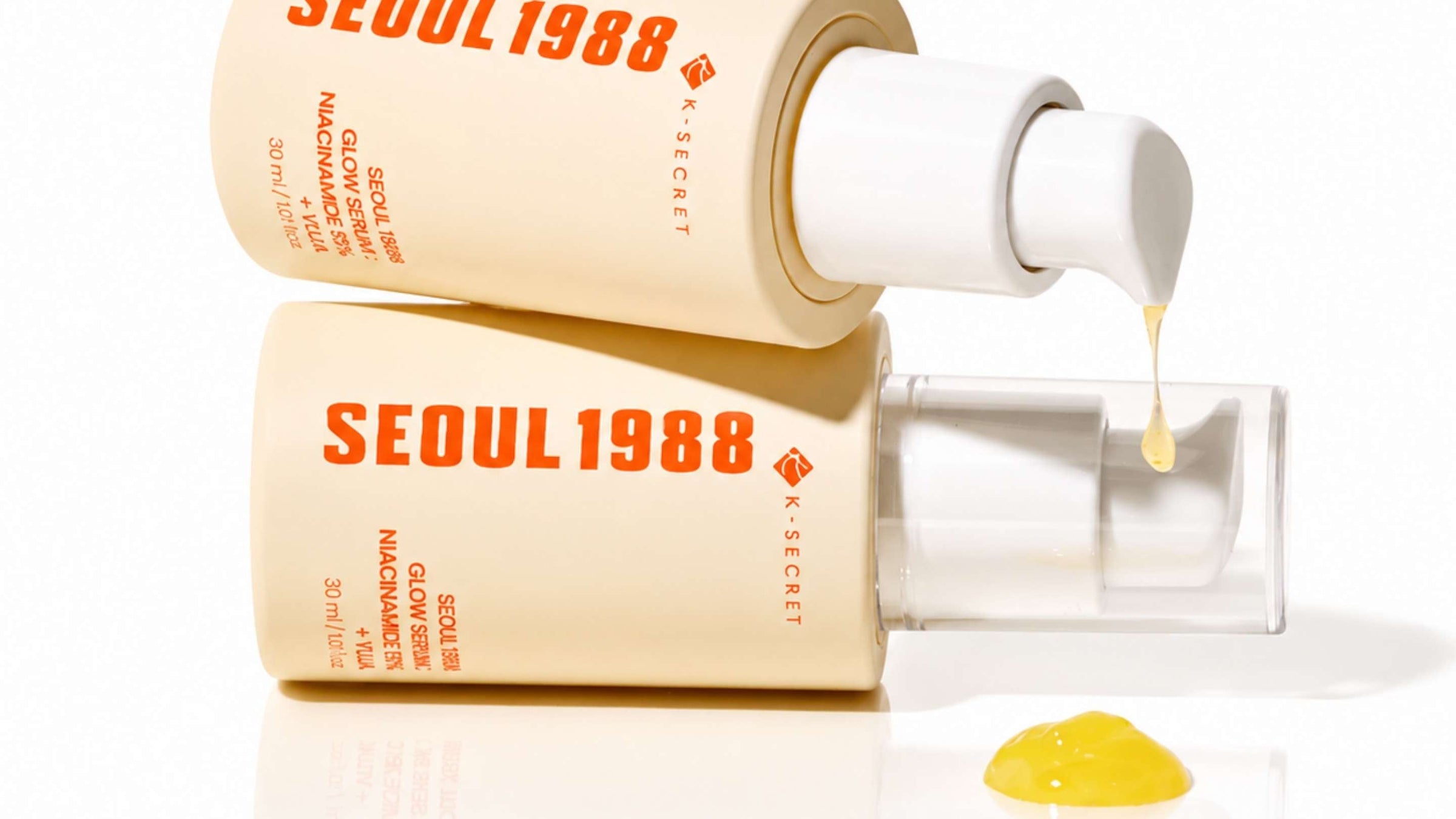Tre tuber av Dark Spot Correcting Glow Serum med gröna lock, liggande på en ljus bakgrund. Tuberna är märkta med aktiva ingredienser som niacinamide och squalane för att förbättra hudens lyster och minska mörka fläckar.