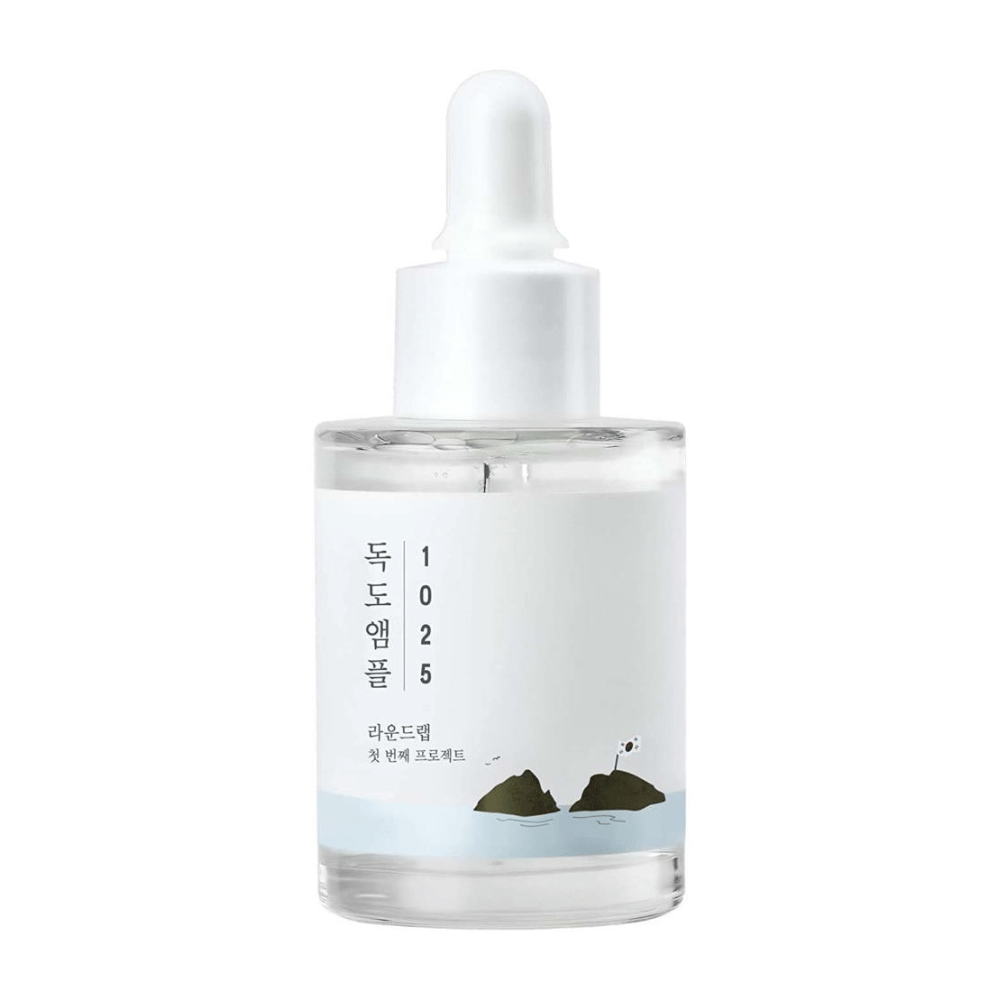 Läpinäkyvä pullo 1025 Dokdo Ampoule kasvoseerumia, koristeltu minimalistisella meriteemalla, valkoisella taustalla.