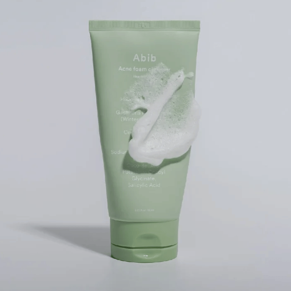 Vihreä tuubi Abib Acne Foam Cleanser Heartleaf, peitettynä valkoisella vaahdolla, joka kuvaa vaahtoavan puhdistusvaikutuksen. Tuote sisältää sydänlehtiuutetta ja salisyylihappoa aknealtteille iholle.