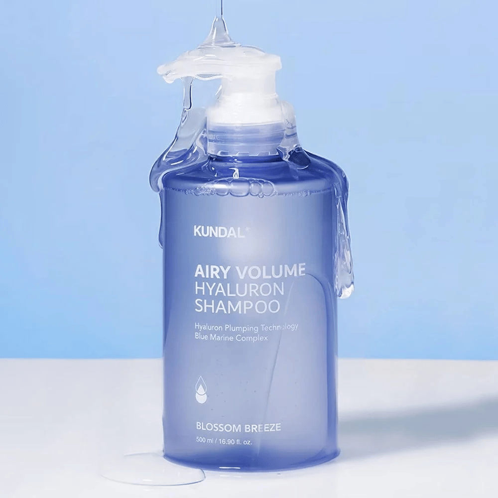 KUNDAL Airy Volume Hyaluron Shampoo Blossom Breeze sinisessä pumppupullossa, hyaluronilla ja Blue Marine Complexilla, kuvattu juoksevan veden kanssa.