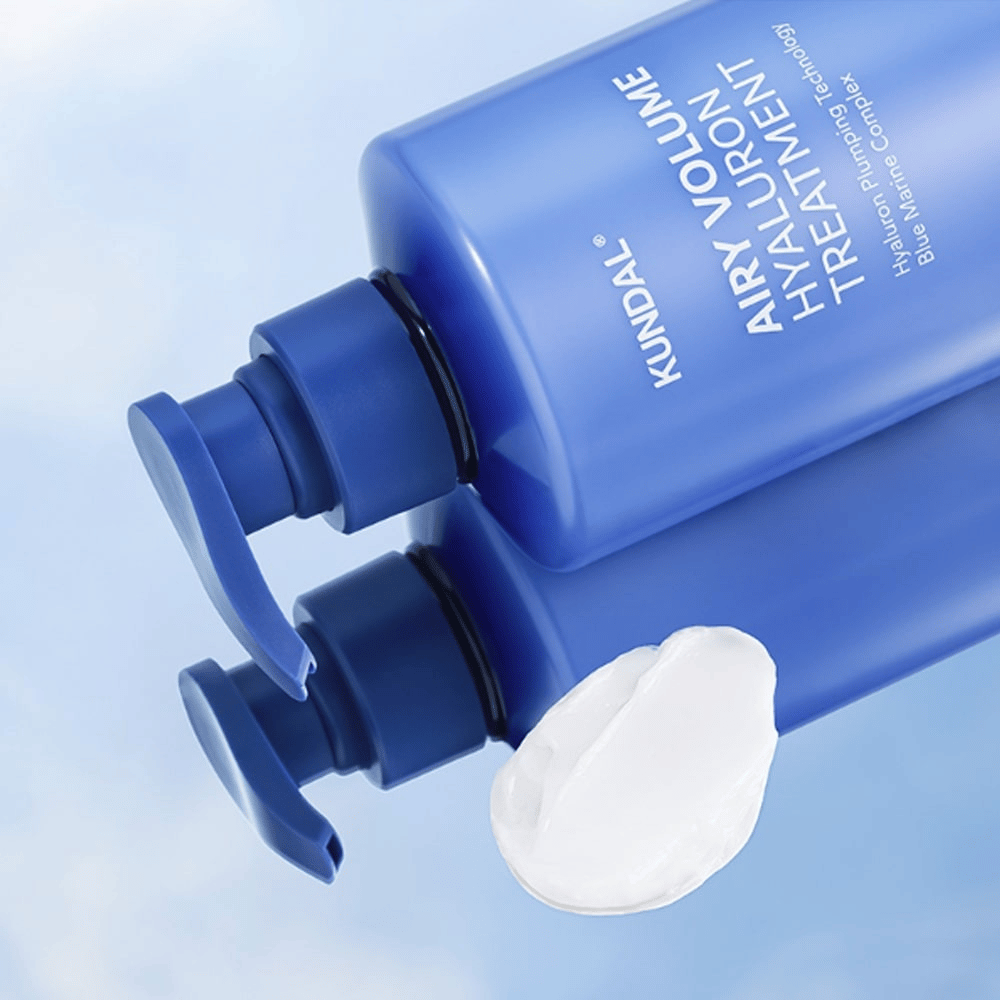 KUNDAL Airy Volume Hyaluron Treatment sinisessä pumppupullossa makuullaan, valkoinen voide näkyvissä vieressä.