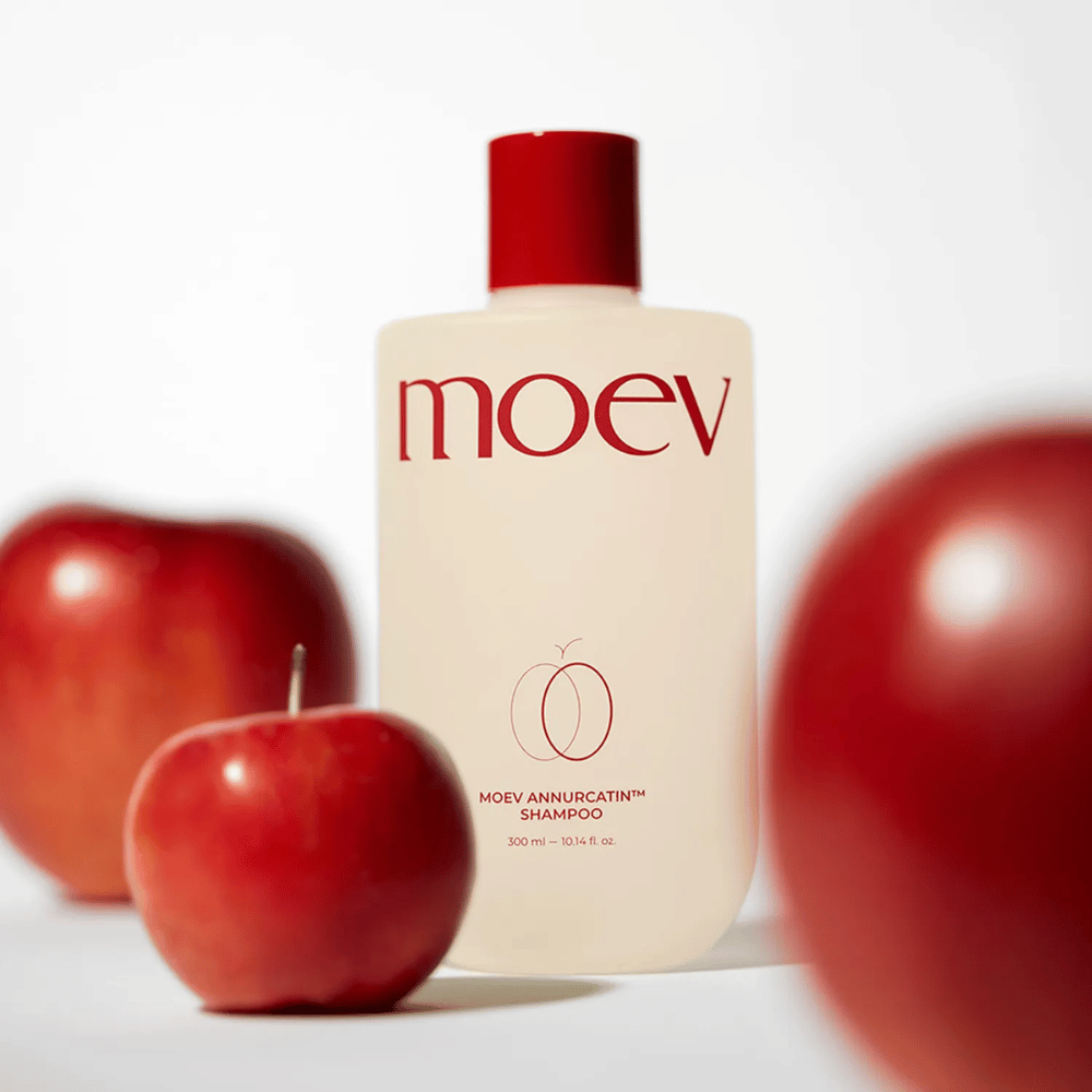 MOEV Annurcatin Shampoo sijoitettu punaisten omenoiden joukkoon – inspiroitunut Annurca-omenan antioksidanteista, jotka antavat vahvempia, terveempiä ja kiiltävämpiä hiuksia.