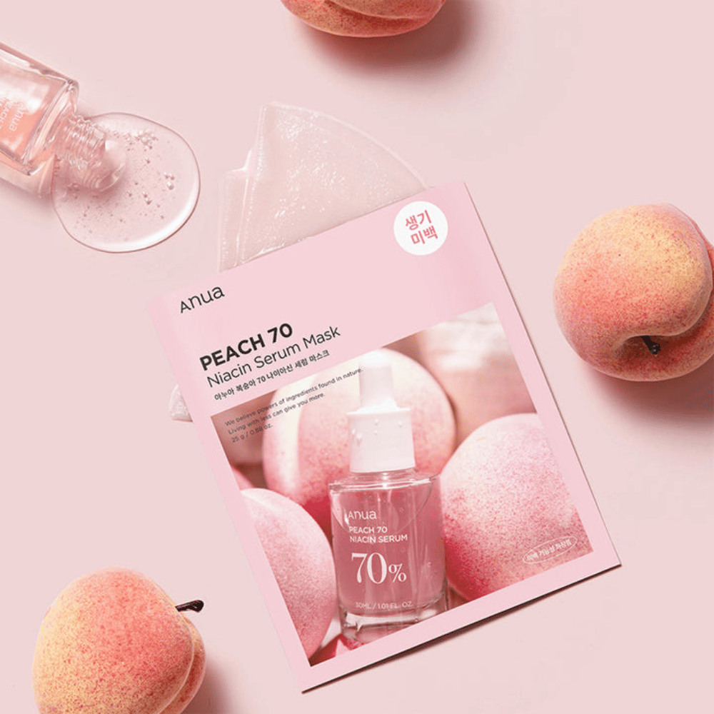 Kuva Anua PEACH 70 Niacin Serum Maskista, jota ympäröivät persikat ja seerumipullo. Kuvassa on pehmeä vaaleanpunainen tausta, joka täydentää vaaleanpunaista pakkausta ja korostaa tuotetta ja ainesosia.