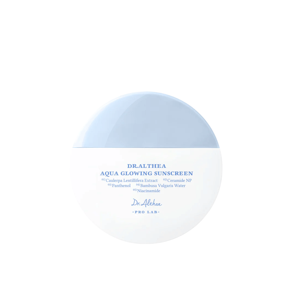 Tuotekuva Dr. Althea Aqua Glowing Sunscreen – pyöreä aurinkosuojavoide valkoisessa ja vaaleansinisessä pakkauksessa, jossa on sininen teksti, joka korostaa kosteuttavia ainesosia kuten niasiiniamidi ja keramidit.