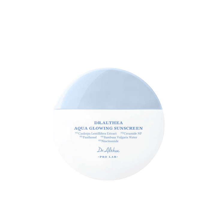 Produktbild av Dr. Althea Aqua Glowing Sunscreen – en rund solskyddskräm i vit och ljusblå förpackning med text i blått som lyfter fram återfuktande ingredienser som niacinamid och ceramider.