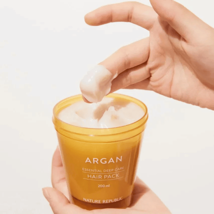 Hand tar upp den krämiga formulan från Nature Republic Argan Essential Moisture Repairing Hair Mask – intensiv näring för torrt hår.