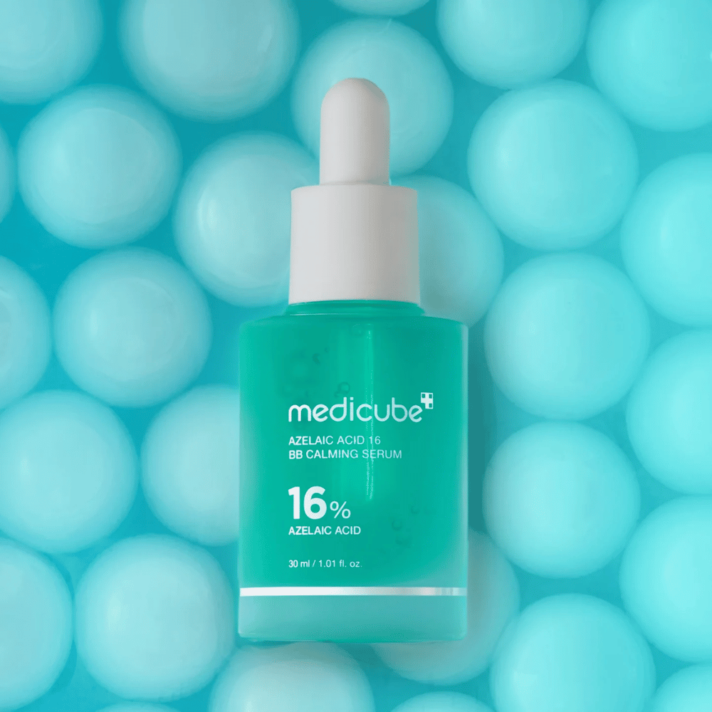 Kampanjakuva tuotteesta Medicube Azelaic Acid 16 BB Calming Serum turkoosia taustaa vasten pehmeiden pallojen kanssa, jotka symboloivat kosteutusta, rauhoittavaa vaikutusta ja tasaisempaa ihon rakennetta.