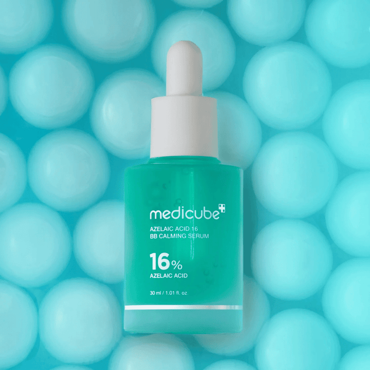 Kampanjakuva tuotteesta Medicube Azelaic Acid 16 BB Calming Serum turkoosia taustaa vasten pehmeiden pallojen kanssa, jotka symboloivat kosteutusta, rauhoittavaa vaikutusta ja tasaisempaa ihon rakennetta.