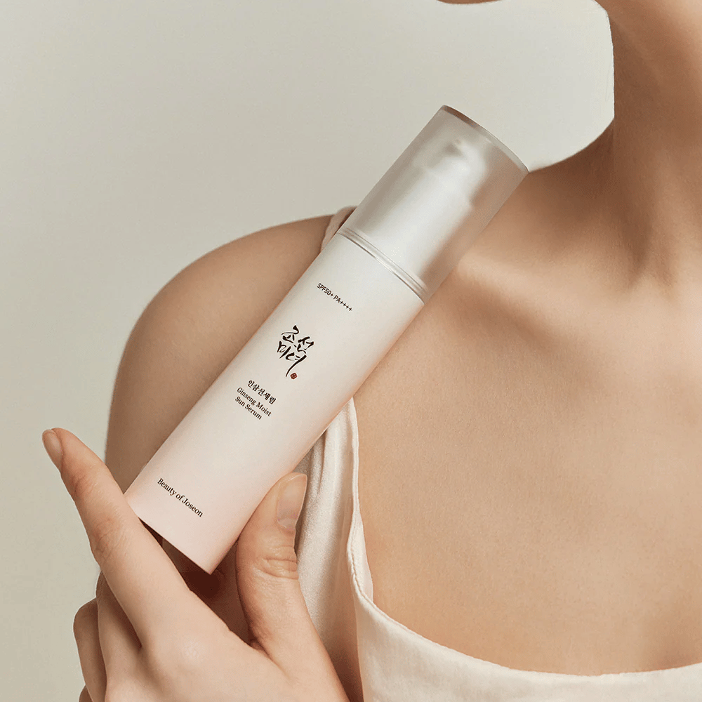 Nainen, joka pitää kädessään pulloa Beauty of Joseon's Ginseng Moist Sun Serum SPF 50+ PA++++, joka tarjoaa SPF 50+ PA++++ -suojan ja ihonhoitoedut.