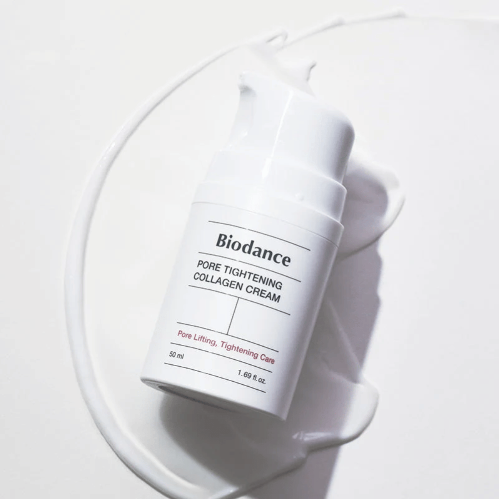 Biodance Pore Tightening Collagen Cream valkoisessa pumppupullossa, makaa valkoisen voiteen pyörteessä.