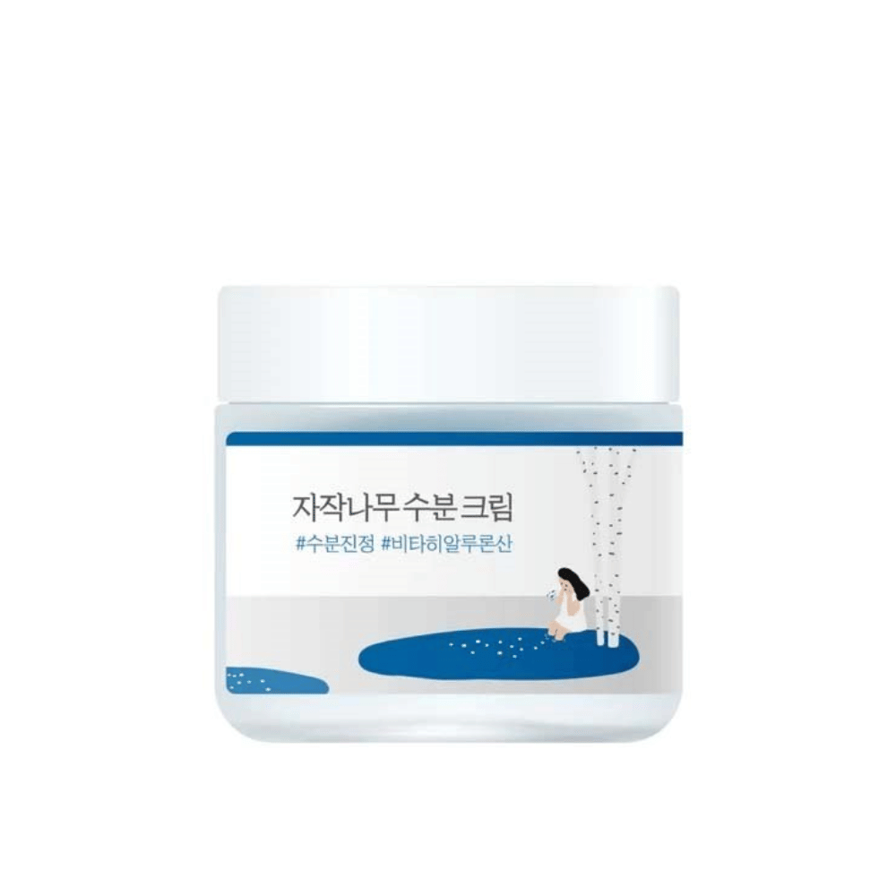 Round Lab Birch Juice Moisturizing Cream läpinäkyvässä purkissa, jossa on valkoinen kansi ja sininen etiketti, jossa on koivun ja tytön kuva, valkoista taustaa vasten.