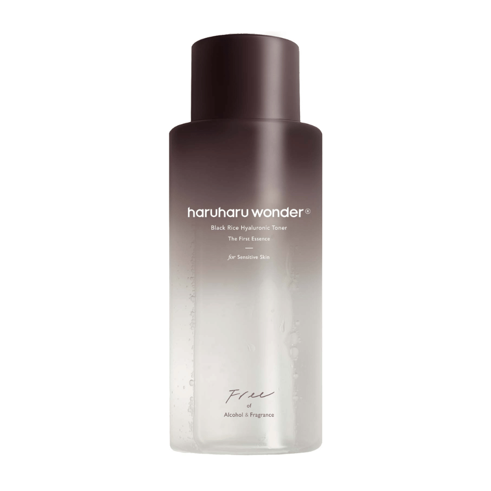 Pullo haruharu wonder Black Rice Hyaluronic Toner The First Essencea, tummanruskeasta läpinäkyvään gradienttiin ja tekstillä "Free of Alcohol & Fragrance", valkoisella taustalla.