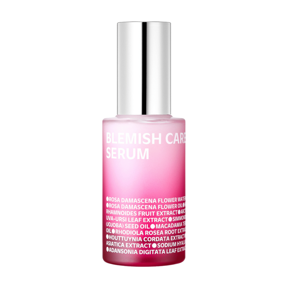 Yksinäinen Blemish Care Serum -pullo, jossa on ylitoneroitu vaaleanpunainen muotoilu ja hopeanvärinen korkki, seisoo valkoista taustaa vasten. Pullon teksti listaa ainesosina muun muassa ruusuvettä, öljyjä ja uutteita, painettuna valkoisella etupuolelle.