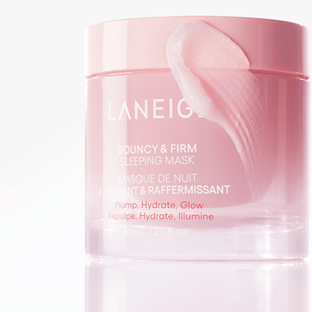 Lähikuva Laneige Bouncy & Firm Sleeping Mask vaaleanpunaisessa purkissa, jossa osa naamiosta on levitetty kannen reunalle. Tuote on tarkoitettu antamaan täyteläisyyttä, kosteutusta ja hehkua. Purkki sisältää 60 ml ja siinä on teksti "Täyteläisyys, Kosteutus, Hehku."