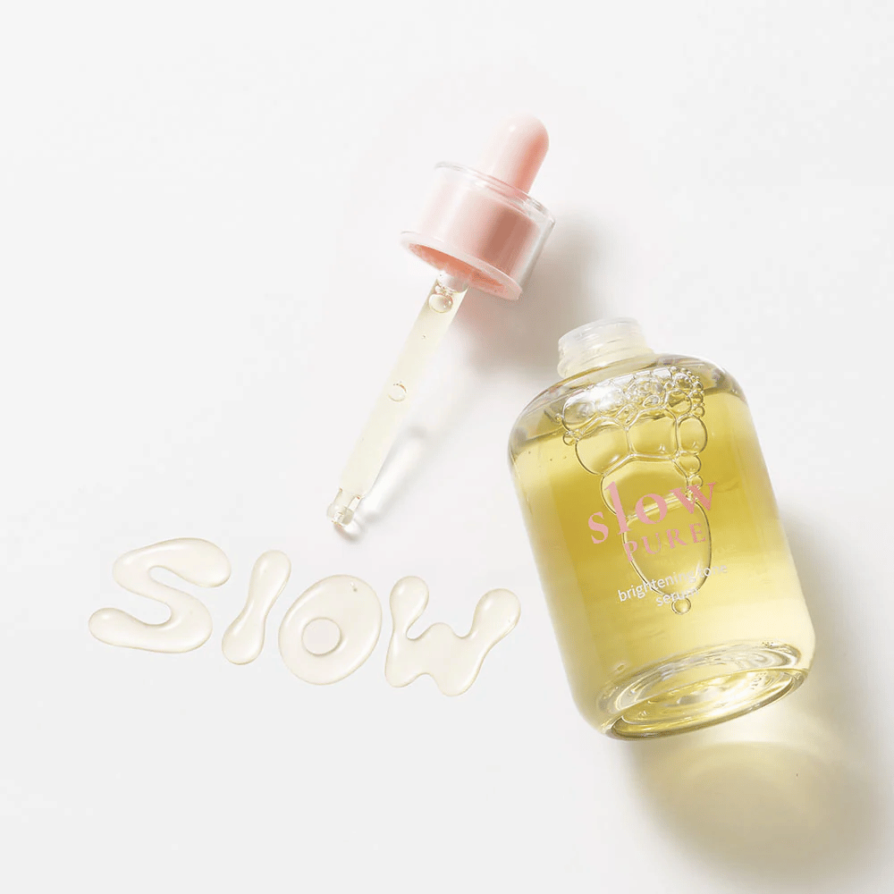 Slow Pure Brightening Tone Serum avoimella pipetillä, teksti kirjoitettu seerumiin pinnalla: "Slow".