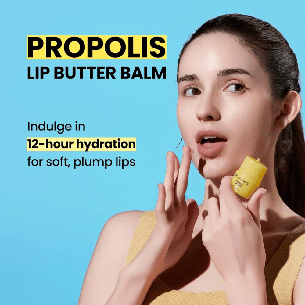 Nainen levittää CNP Laboratory Propolis Lip Butter Balm -huulivoidetta, korostettuna sinistä taustaa vasten. Tuote lupaa 12 tunnin kosteutuksen pehmeille ja täyteläisille huulille, mikä näkyy hänen kädessään olevassa keltaisessa tuubissa.