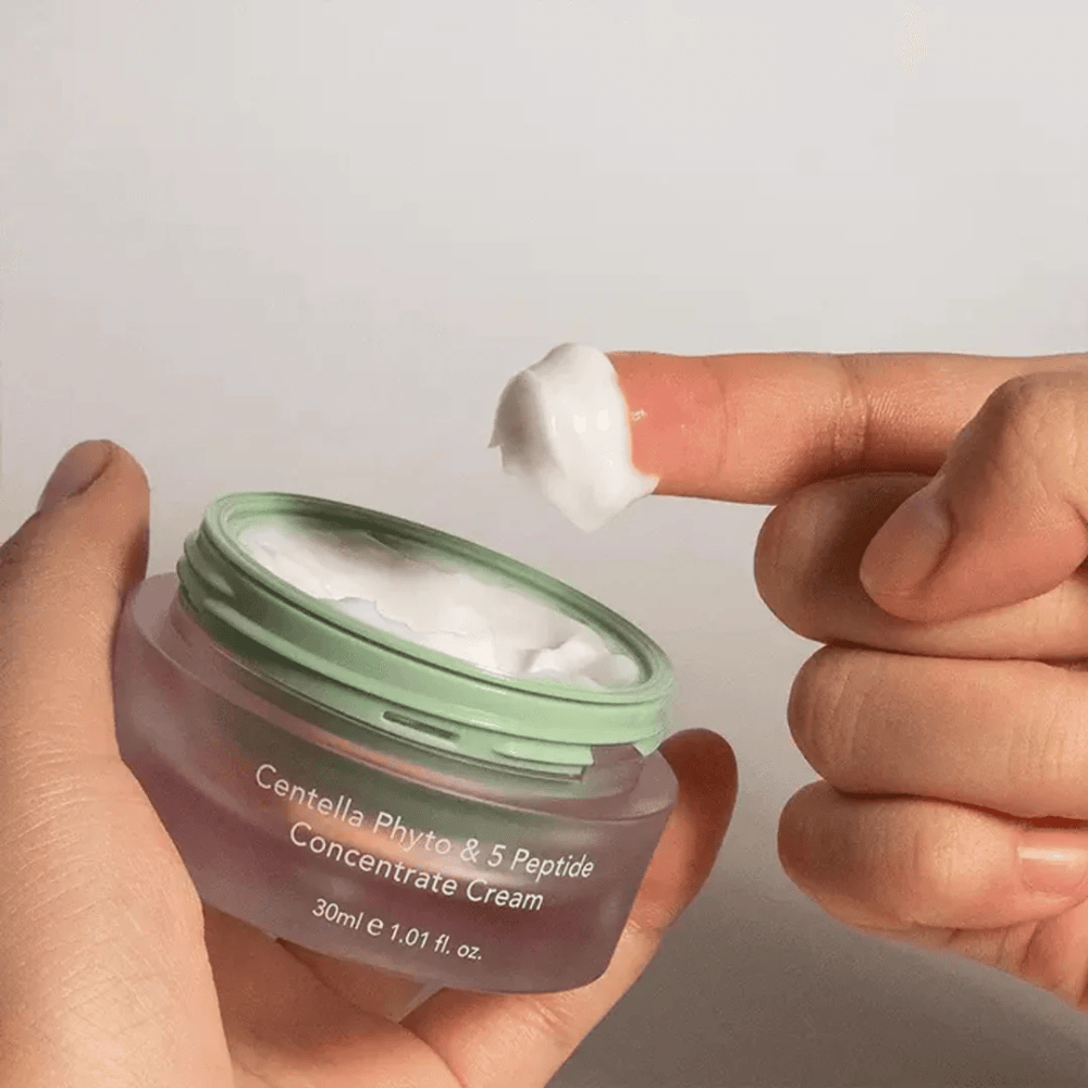 Käsi ottaa nokareen Centella Phyto & 5 Peptide Concentrate Cream purkista.