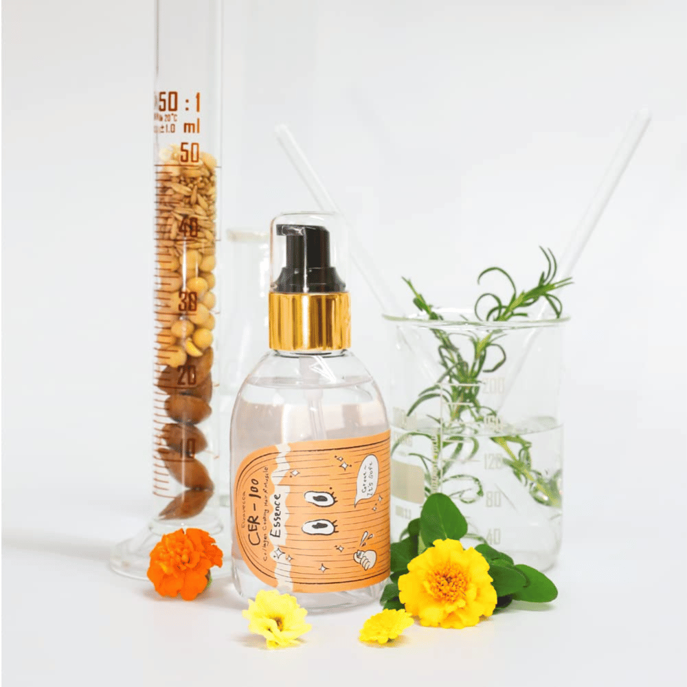 CER-100 Hair Essence yhdessä kukkien ja laboratoriolasien kanssa, jotka korostavat ainesosia ja hiustenhoitoa.