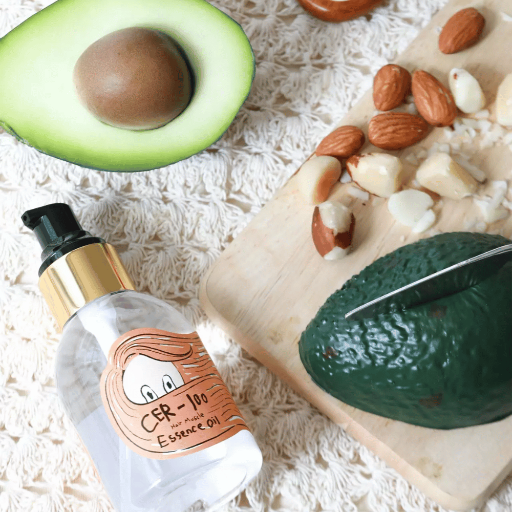 Elizavecca CER-100 Hair Muscle Essence Oil ainesosat – lähikuva avokadosta ja kasviöljyistä, joka esittelee ravitsevan hiusöljyn, joka auttaa pehmentämään ja hoitamaan hiuksia.