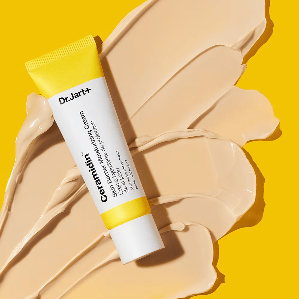 Tuuppi Dr. Jart+ Ceramidin Skin Barrier Moisturizing Cream keltaista taustaa vasten, jossa on levitettyä voidetta.