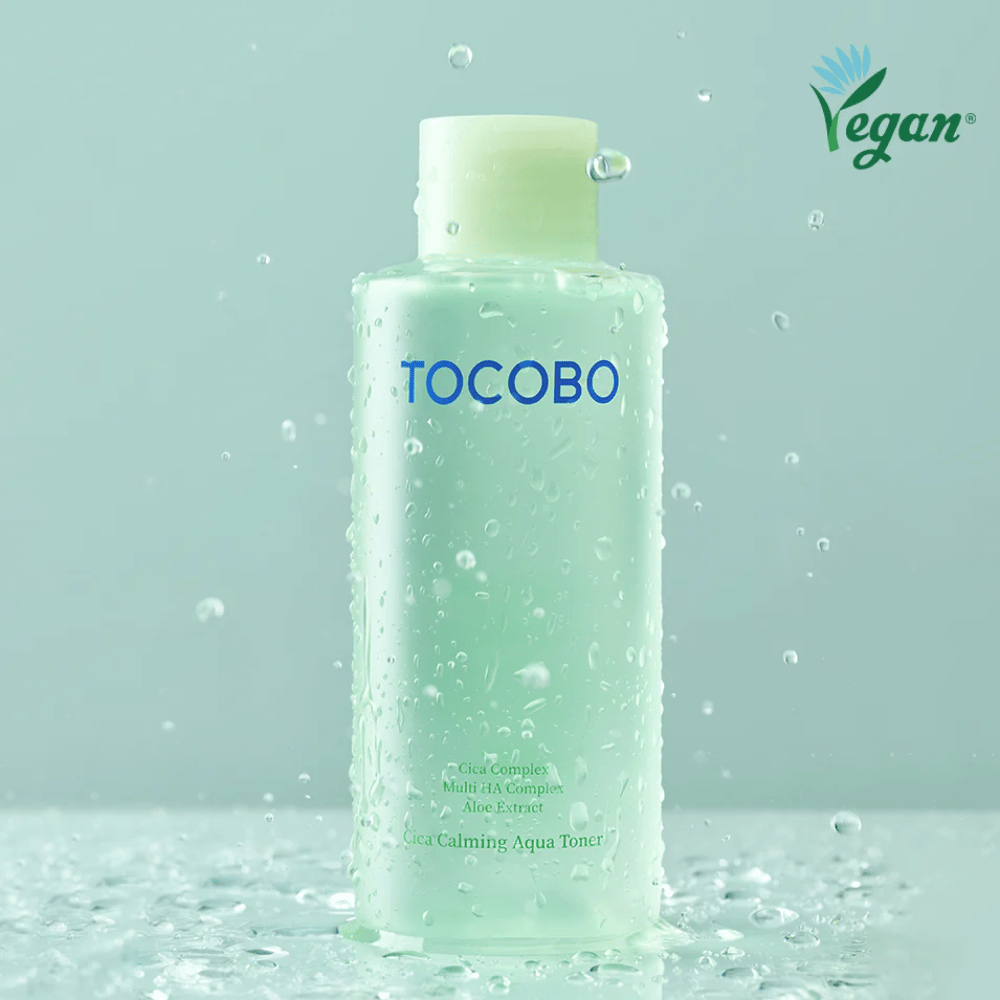 Tuotekuva tuotteesta TOCOBO Cica Calming Aqua Toner, jota ympäröivät vesipisarat korostavat kasvoveden kosteuttavia ja rauhoittavia ominaisuuksia herkälle iholle.