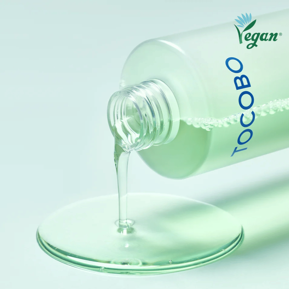Lähikuva tuotteesta TOCOBO Cica Calming Aqua Toner, jota kaadetaan esiin tuotteen kirkkaan, kevyen ja viilentävän koostumuksen korostamiseksi.
