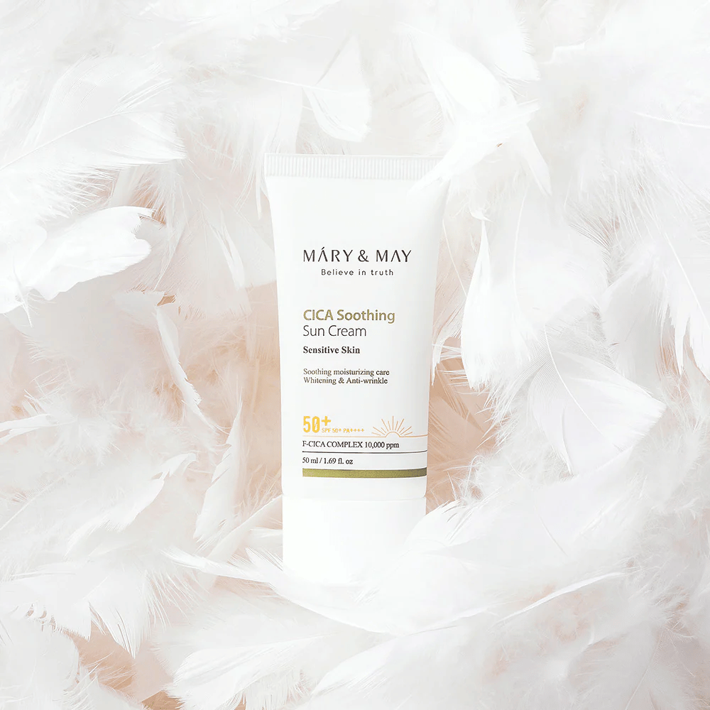 Mary&May CICA Soothing Sun Cream pehmeiden valkoisten höyhenten ympäröimänä. Kuva välittää hellävaraisuuden, mukavuuden ja kevyen koostumuksen tunteen, joka sopii herkälle iholle.