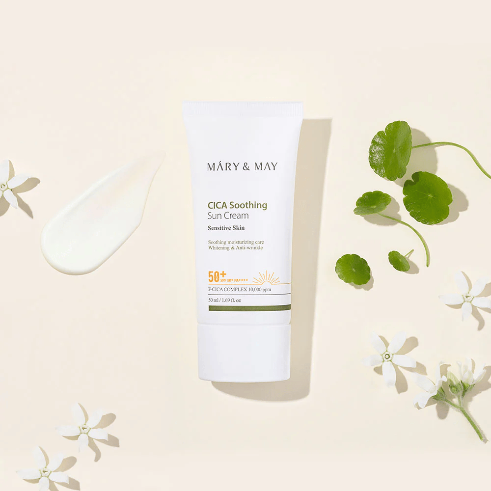Mary&May CICA Soothing Sun Cream SPF50+ PA++++ esiteltynä yhdessä voidemaisen koostumuksen, centella-lehtien ja valkoisten kukkien kanssa. Kuva tuo esiin tuotteen rauhoittavat ominaisuudet ja keskittymisen herkälle iholle.