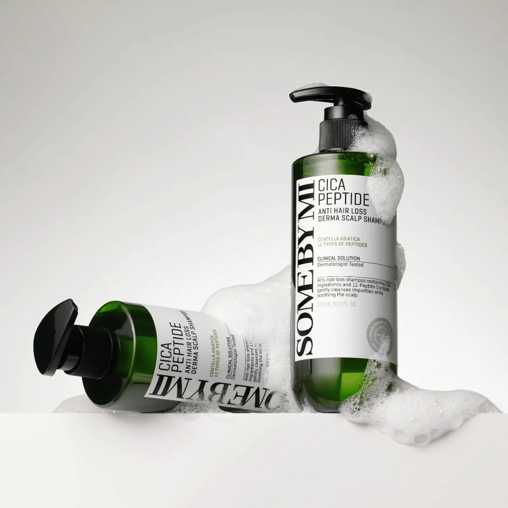 Kaksi pulloa SOME BY MI Cica Peptide Anti Hair Loss Derma Scalp Shampoo peitettynä vaahdolla, seisten ja makuulla valkoista taustaa vasten.