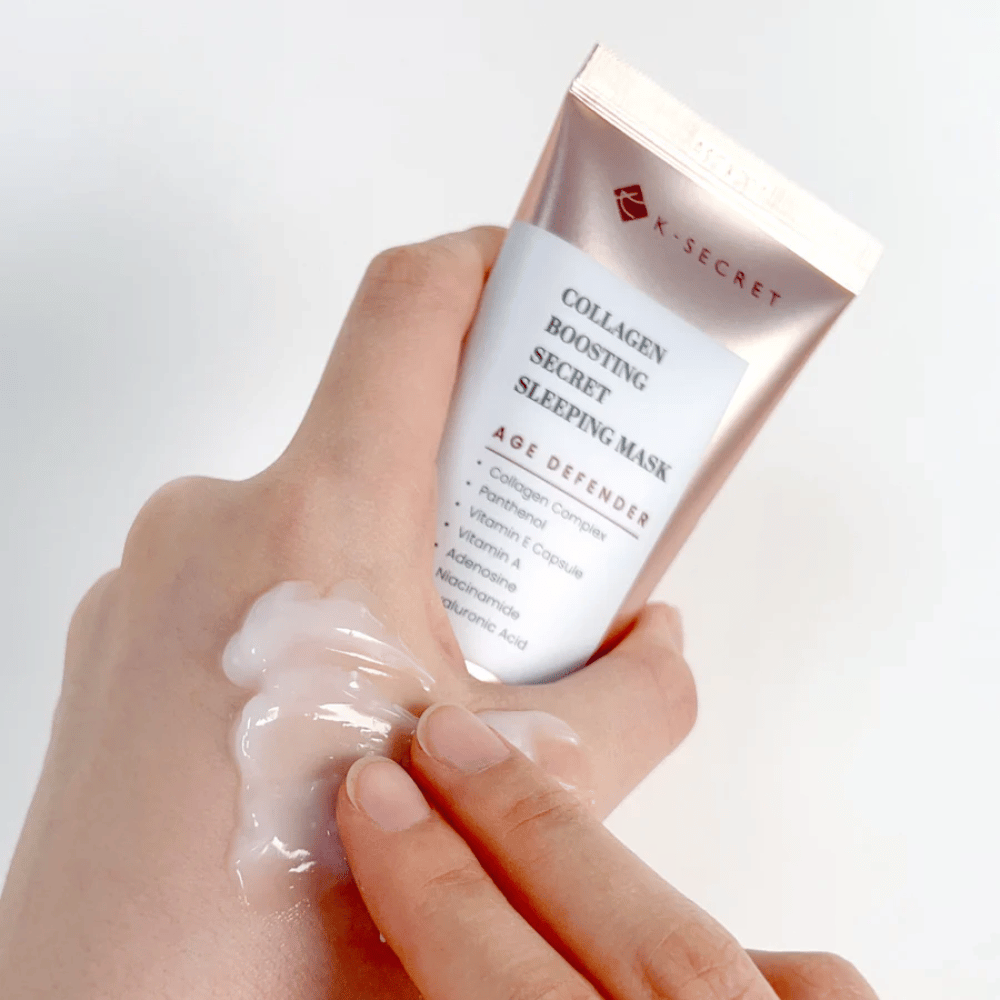 Käsi pitää Collagen Boosting Secret Sleeping Mask toisessa kädessä samalla kun toinen käsi levittää runsaan määrän voidetta käden päälle – näyttää tuotteen koostumuksen ja levityksen.