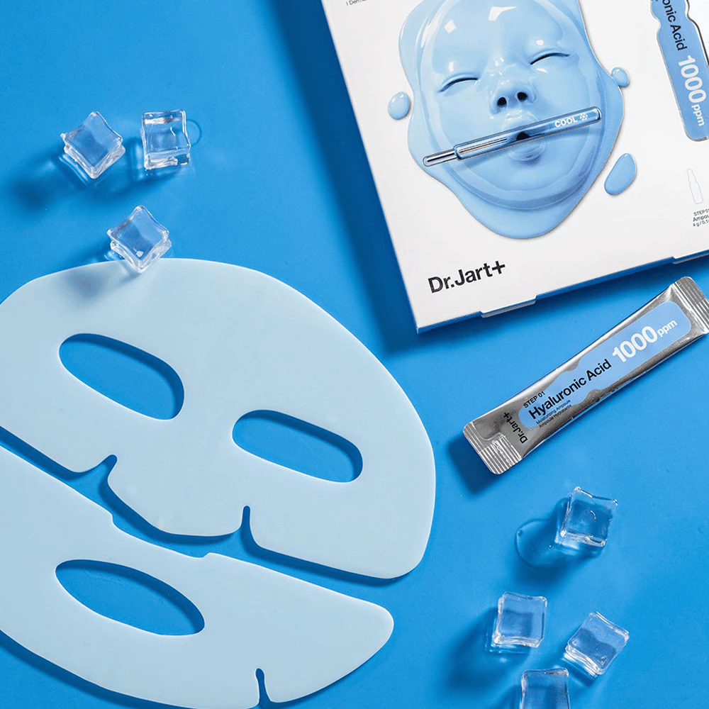 Dr.Jart+ Cryo Rubber Moisturizing Mask kaksiosaisella sinisellä kuminaamiolla, jääpaloilla, hyaluronihappoampullilla ja pakkauksella sinistä taustaa vasten.