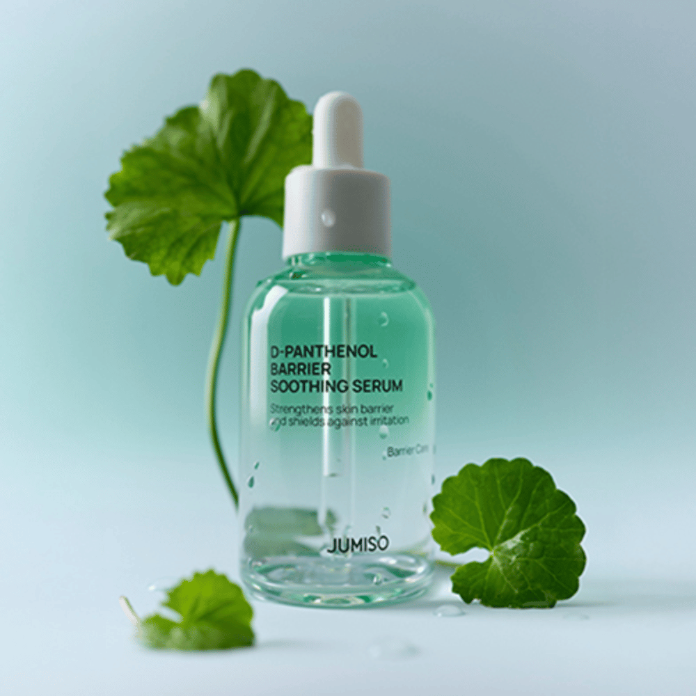 Jumiso D-Panthenol Barrier Soothing Serum läpinäkyvässä lasipullossa pipetillä, asetettuna vihreiden lehtien taustalle.