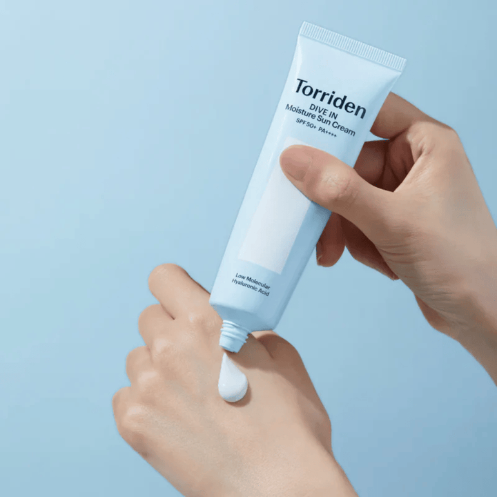 Torriden DIVE-IN Moisture Sun Cream SPF50+ PA++++ levitetään kädelle, jotta kosteuttavan aurinkovoiteen kevyt ja voidemainen koostumus tulee esiin.