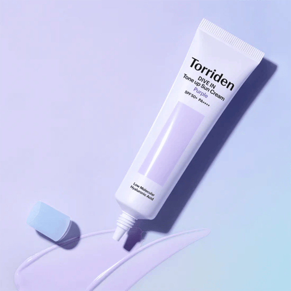 Avattu tuubi Torriden DIVE IN Tone Up Sun Cream Purple, jossa on violetinsävyinen aurinkovoidekoostumus ja joka näyttää tuotteen väriä korjaavan formulan.