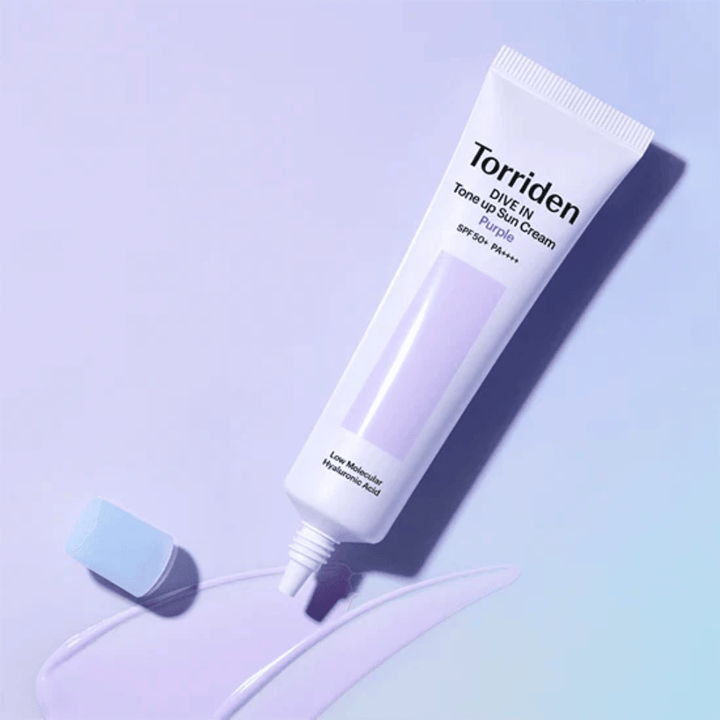 Avattu tuubi Torriden DIVE IN Tone Up Sun Cream Purple, jossa on violetinsävyinen aurinkovoidekoostumus ja joka näyttää tuotteen väriä korjaavan formulan.