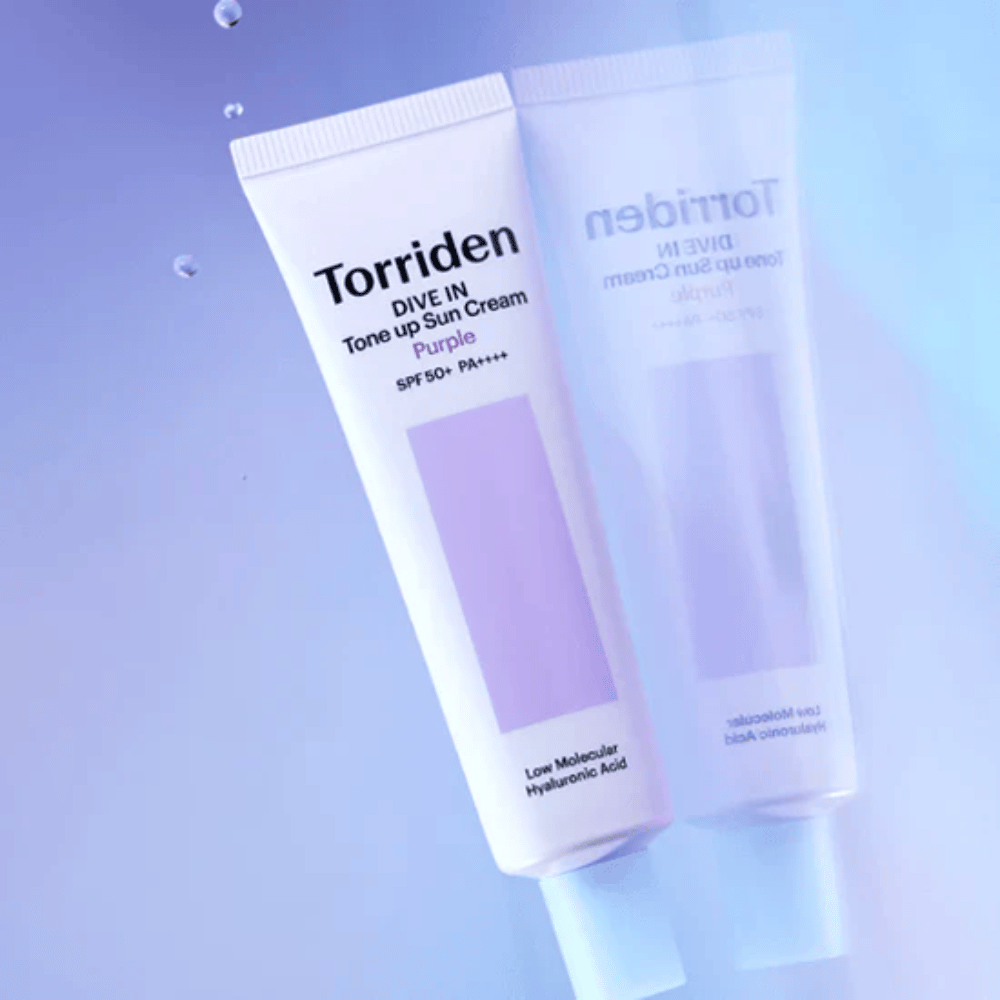 Torriden DIVE IN Tone Up Sun Cream Purple SPF50+ PA++++ kuvattuna pehmeää violettia taustaa vasten, joka korostaa tuotteen valoa heijastavaa muotoilua.