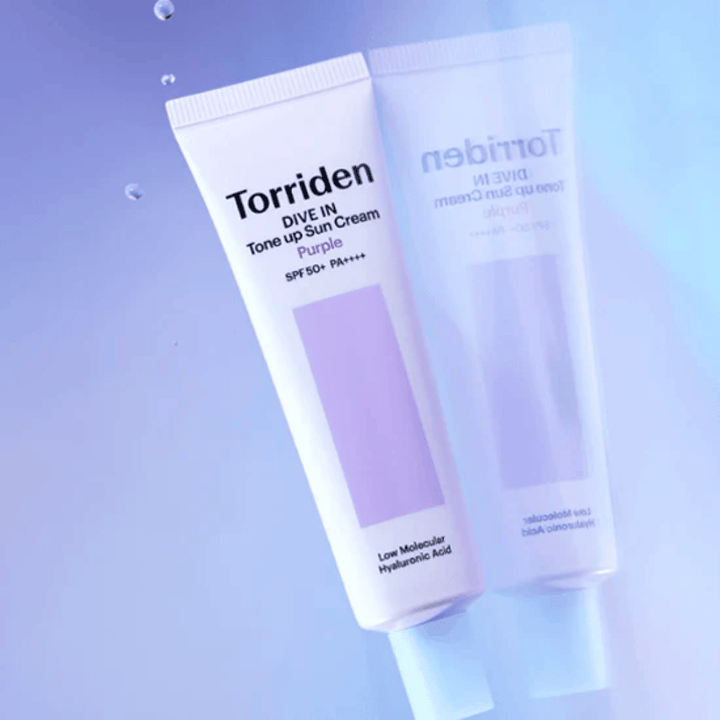 Torriden DIVE IN Tone Up Sun Cream Purple SPF50+ PA++++ kuvattuna pehmeää violettia taustaa vasten, joka korostaa tuotteen valoa heijastavaa muotoilua.