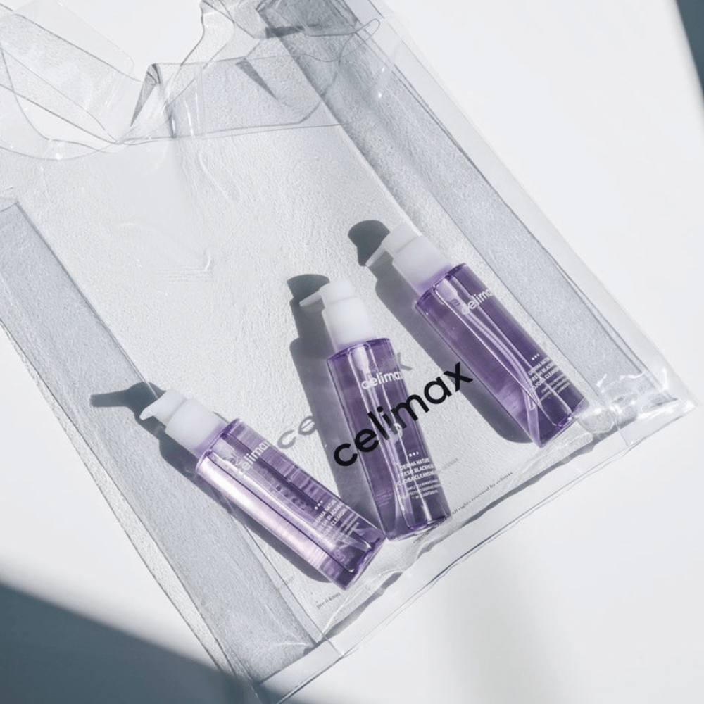 Kolme pulloa Celimax Derma Nature Fresh Blackhead Jojoba Cleansing Oil violetissa pakkauksessa, sijoitettuna läpinäkyvään pussiin, jossa on logo 'celimax'.