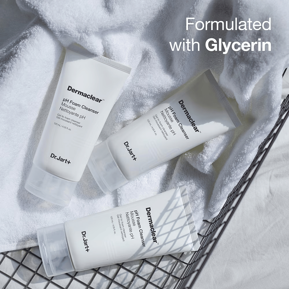 Kolme Dr.Jart+ Dermaclear pH Foam Cleanser -putkea makaavat valkoisella froteepyyhkeellä metallikorissa, tekstillä "Formulated with Glycerin" yläkulmassa.