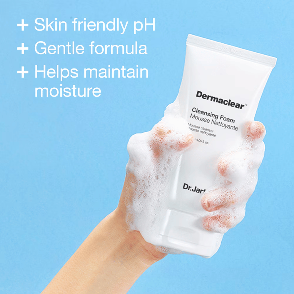 Kädessä, joka on peitetty vaahdolla, pidetään Dr.Jart+ Dermaclear Cleansing Foam sinistä taustaa vasten, tekstillä, joka korostaa ihoystävällistä pH:ta, mietoa koostumusta ja kosteuttavia ominaisuuksia.