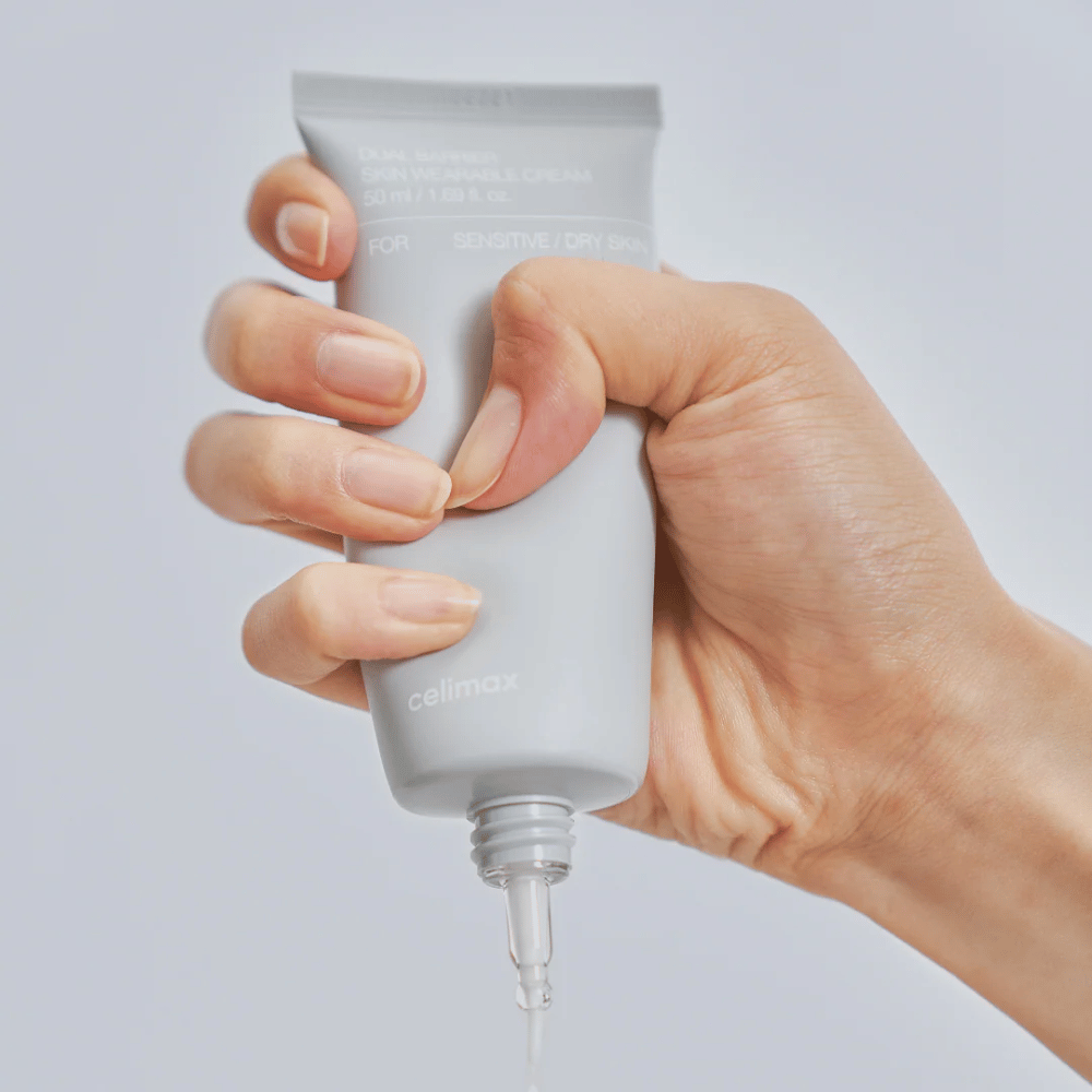 Käsi levittää Celimax Dual Barrier Skin Wearable Cream, suojamuuria vahvistava kasvovoide herkälle ja kuivalle iholle, joka tarjoaa pitkäkestoista kosteutusta ja suojaa ihon suojamuuria.