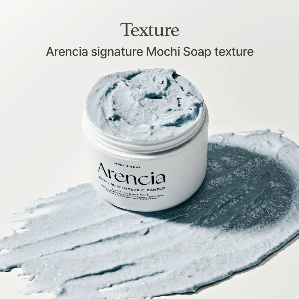 Avoin purkki Arencia Fresh Blue Hyssop Rice Mochi Cleanser, sijoitettuna levitetyn kerroksen päälle sinistä, kermaista puhdistusainetta, joka näyttää sen mochi-tyyppisen koostumuksen.