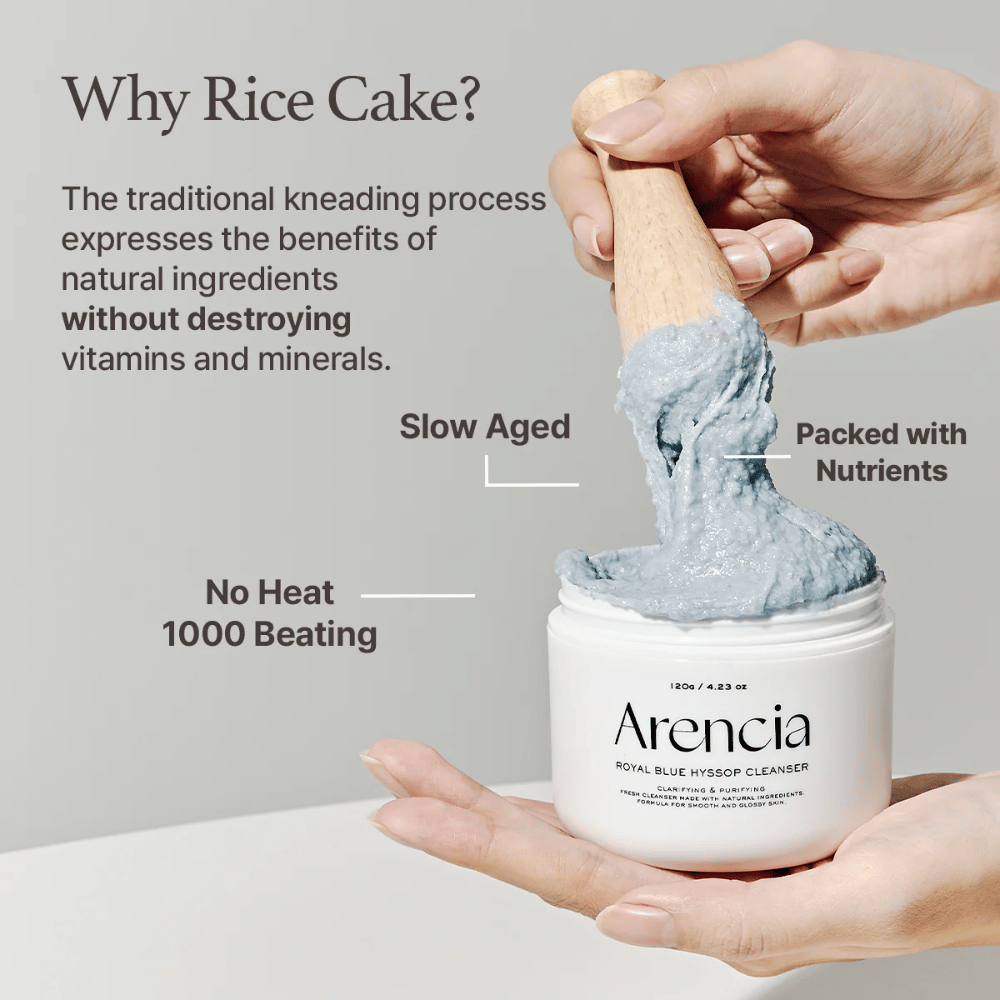 Käsi pitelee puhdistuspurkkia "Arencia Royal Blue Hyssop Cleanser" puulusikalla, joka nostaa sinistä, mochi-tyyppistä puhdistuspastaa. Kuvan teksti kuvailee riisitaikinaprosessin etuja, kuten "No Heat", "1000 Beating", "Slow Aged" ja "Packed with Nutrients".