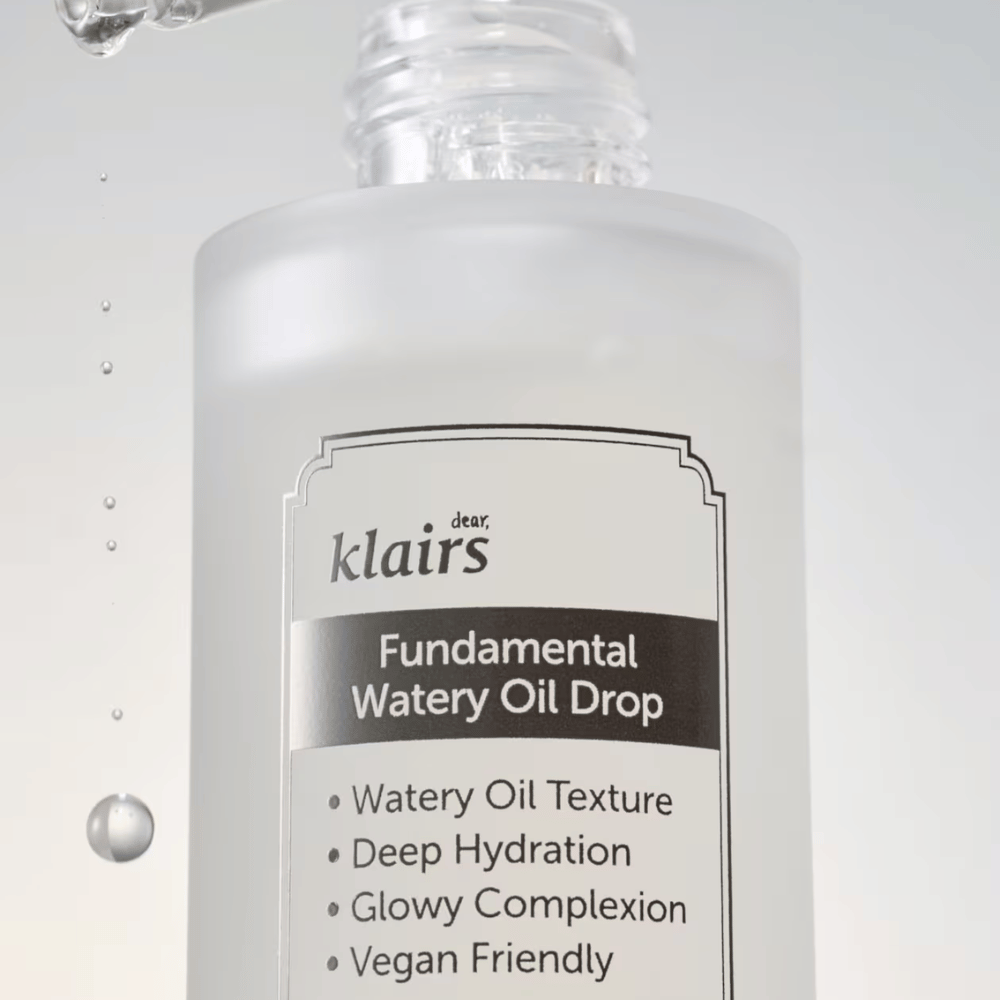Lähikuva pullosta Klairs Fundamental Watery Oil Drop, tekstillä, joka korostaa tuotteen ominaisuuksia, kuten "Watery Oil Texture", "Deep Hydration", "Glowy Complexion" ja "Vegan Friendly".
