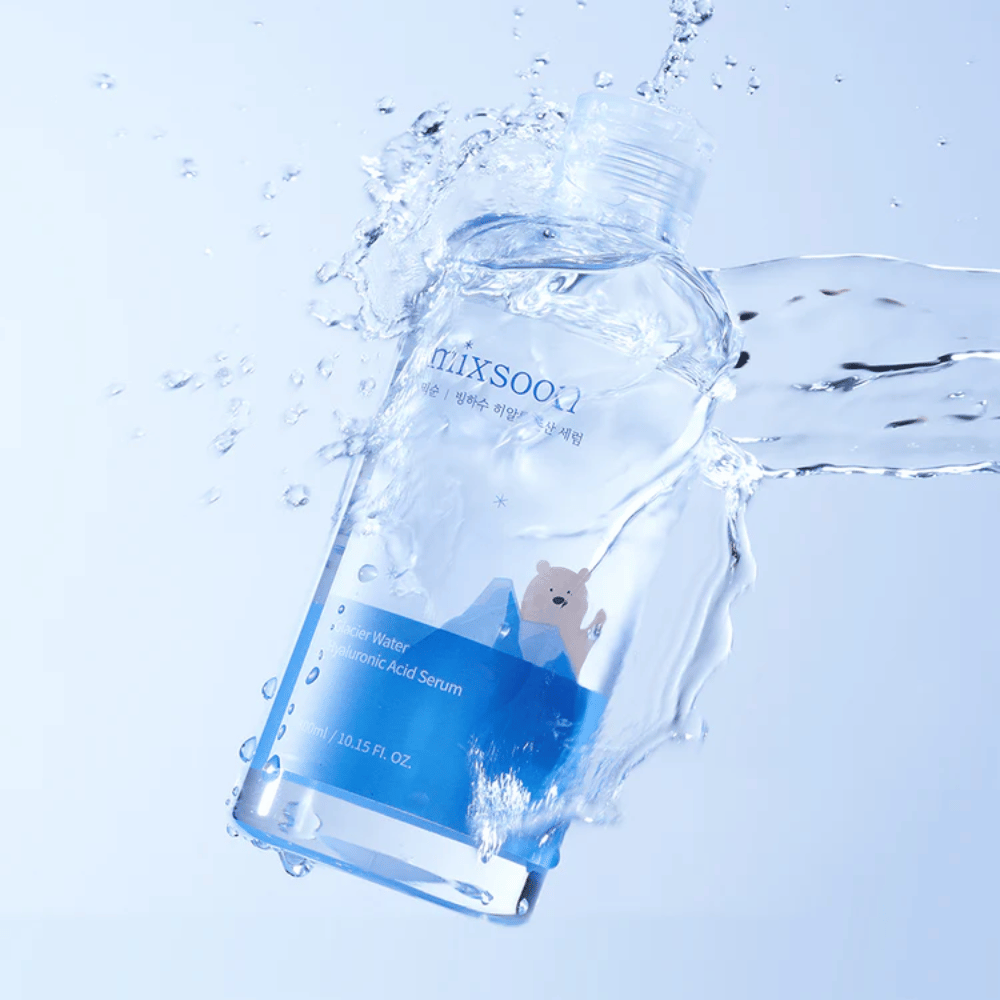Mixsoon Glacier Water Hyaluronic Acid Serum-pullo, jossa on sininen etiketti ja jääkarhukuva, ympärillä roiskuvaa vettä vaaleansinistä taustaa vasten.