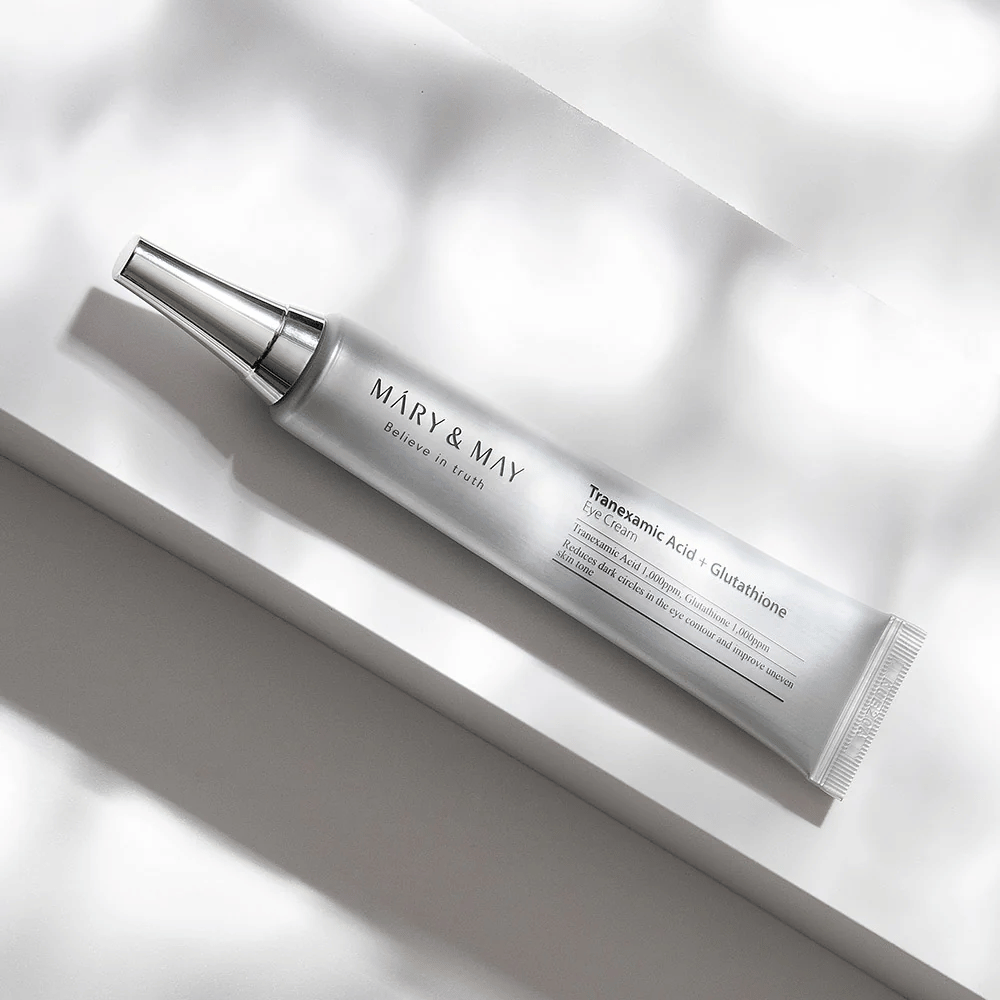 Lähikuva Mary&May Tranexamic Acid + Glutathione Eye Cream metalliapplikaattorilla, kehitetty kirkastamaan tummia silmänalusia ja tasoittamaan ihon sävyä silmien ympärillä.