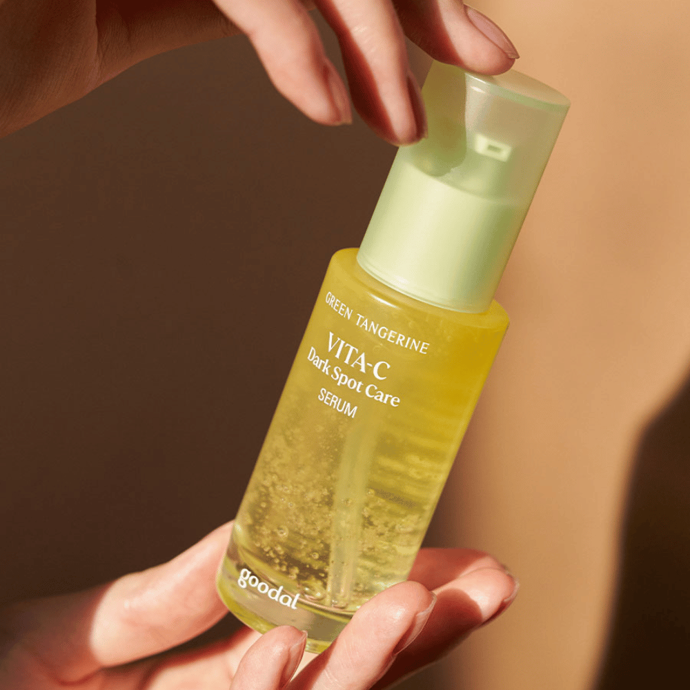 Henkilö, joka pitelee pulloa Green Tangerine Vita C Dark Spot Care Serum 40ml Goodal hyperpigmentaatiota ja tummien läiskien hoitoa varten.