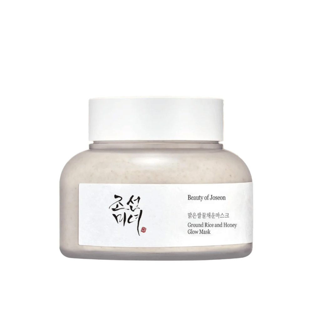 Tölkki "Beauty of Joseon Ground Rice and Honey Glow Mask". Pakkaus on yksinkertainen valkoisella korkilla ja etiketillä, joka esittelee tuotteen nimen ja ainesosat sekä koreaksi että englanniksi. Tuote on suunniteltu antamaan iholle hehkua ja ravintoa.