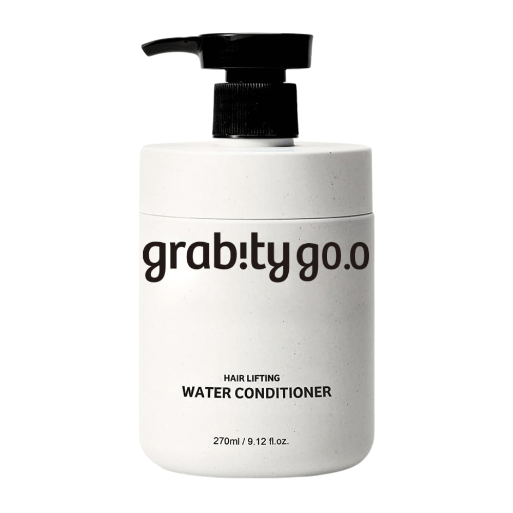 Grabity Hair Lifting Water Conditioner tyylikkäässä valkoisessa pumppupullossa vaaleaa taustaa vasten. Volyymia antava hoitoainekoostumus, joka on kehitetty antamaan pehmeyttä, kiiltoa ja täyteläisemmän vaikutelman hiuksille.