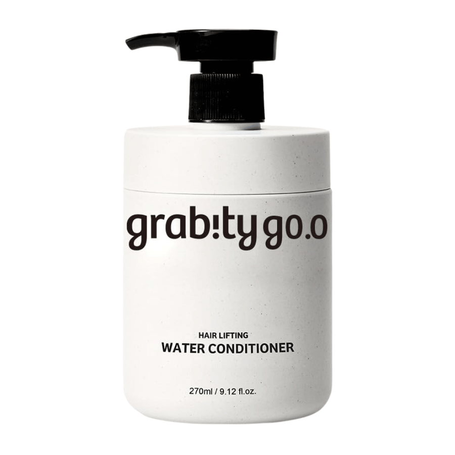 Grabity Hair Lifting Water Conditioner tyylikkäässä valkoisessa pumppupullossa vaaleaa taustaa vasten. Volyymia antava hoitoainekoostumus, joka on kehitetty antamaan pehmeyttä, kiiltoa ja täyteläisemmän vaikutelman hiuksille.